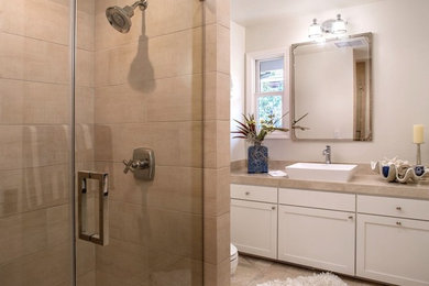 Design ideas for a medium sized beach style family bathroom in San Francisco with shaker cabinets, white cabinets, an alcove shower, a one-piece toilet, multi-coloured tiles, stone tiles, white walls, travertine flooring, a vessel sink and marble worktops.