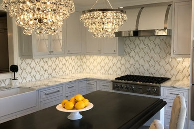 Transitional l-shaped dark wood floor kitchen photo in New York with a farmhouse sink, shaker cabinets, white cabinets, quartzite countertops, stainless steel appliances and an island