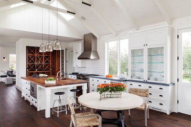 Inspiration for a mid-sized country u-shaped eat-in kitchen in San Francisco with a drop-in sink, raised-panel cabinets, white cabinets, wood benchtops, white splashback, subway tile splashback, stainless steel appliances, dark hardwood floors and with island.