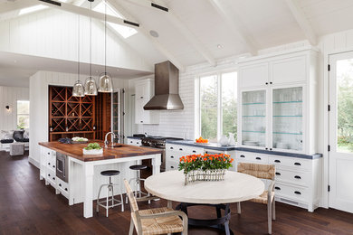 Inspiration for a mid-sized farmhouse u-shaped dark wood floor eat-in kitchen remodel in San Francisco with a drop-in sink, raised-panel cabinets, white cabinets, wood countertops, white backsplash, subway tile backsplash, stainless steel appliances and an island