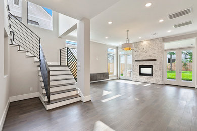 Example of a large trendy open concept dark wood floor and brown floor family room design in Houston with gray walls, a two-sided fireplace, a brick fireplace and a wall-mounted tv