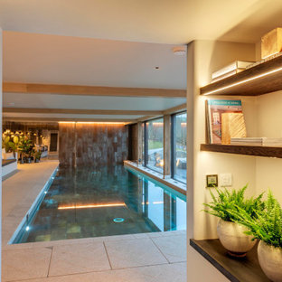 Ejemplo de piscina alargada, costera, grande, interior y rectangular, con privacidad y adoquines de piedra natural
