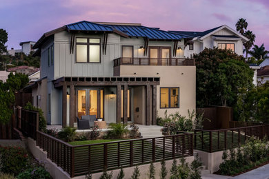 Inspiration for a transitional beige two-story mixed siding house exterior remodel in San Diego with a hip roof and a metal roof