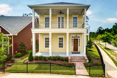 Inspiration for a large timeless yellow two-story vinyl house exterior remodel in New Orleans with a hip roof and a tile roof