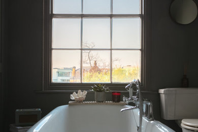 Photo of a large traditional bathroom in London with a claw-foot tub, grey walls and a one-piece toilet.