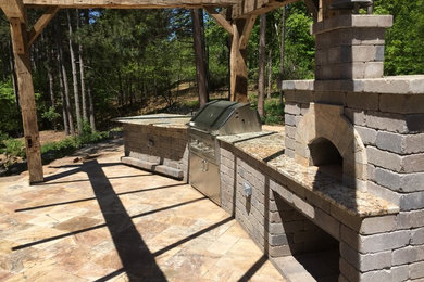 Example of a mid-sized mountain style backyard brick patio kitchen design in Other with a pergola