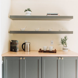 Modern inredning av ett mellanstort grå linjärt grått skafferi, med en undermonterad diskho, skåp i shakerstil, grå skåp, bänkskiva i kvartsit, gult stänkskydd, stänkskydd i porslinskakel, integrerade vitvaror, ljust trägolv, en köksö och beiget golv