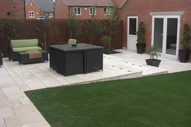 Large modern back formal full sun garden for summer in Other with a garden path and natural stone paving.