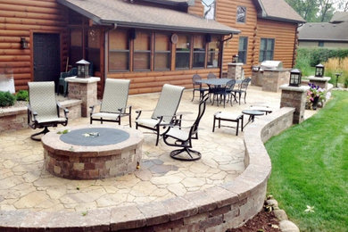 This is an example of a large country backyard patio in Chicago with an outdoor kitchen, natural stone pavers and no cover.