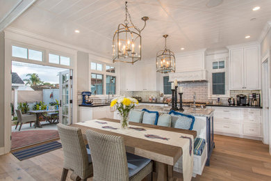 Inspiration for a mid-sized timeless u-shaped light wood floor and beige floor open concept kitchen remodel in San Diego with an undermount sink, shaker cabinets, white cabinets, granite countertops, beige backsplash, porcelain backsplash, stainless steel appliances and an island