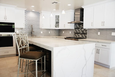 Inspiration for a large transitional l-shaped marble floor and beige floor enclosed kitchen remodel in Orange County with an undermount sink, shaker cabinets, white cabinets, quartz countertops, gray backsplash, glass tile backsplash, stainless steel appliances and an island