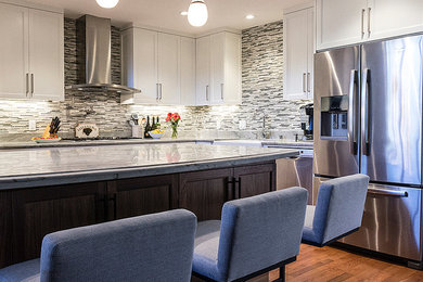 Example of a mid-sized transitional medium tone wood floor kitchen design in San Francisco with a farmhouse sink, shaker cabinets, white cabinets, quartzite countertops, multicolored backsplash, stainless steel appliances and an island
