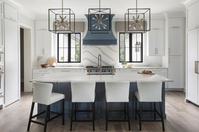 Example of a huge transitional u-shaped brown floor and medium tone wood floor eat-in kitchen design in St Louis with an undermount sink, white cabinets, quartz countertops, quartz backsplash, an island, shaker cabinets, white backsplash, stainless steel appliances and white countertops