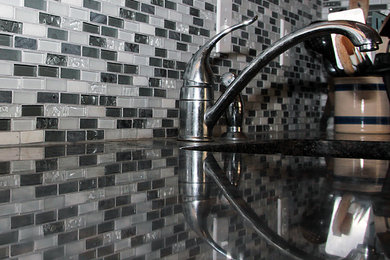 Mid-sized trendy l-shaped medium tone wood floor eat-in kitchen photo in New York with an undermount sink, raised-panel cabinets, medium tone wood cabinets, granite countertops, black backsplash, glass tile backsplash, black appliances and no island