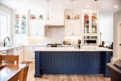 Mid-sized transitional l-shaped eat-in kitchen photo in Toronto with an undermount sink, shaker cabinets, blue cabinets, quartz countertops, gray backsplash, ceramic backsplash, stainless steel appliances, an island and white countertops