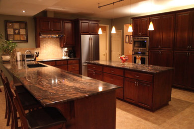 Open concept kitchen - large traditional u-shaped ceramic tile open concept kitchen idea in Portland with an undermount sink, raised-panel cabinets, dark wood cabinets, limestone countertops, beige backsplash, ceramic backsplash, stainless steel appliances and an island