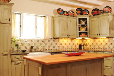 Enclosed kitchen - mid-sized traditional l-shaped brick floor enclosed kitchen idea in Albuquerque with recessed-panel cabinets, distressed cabinets, wood countertops, ceramic backsplash, stainless steel appliances and an island