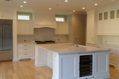 Enclosed kitchen - large traditional single-wall light wood floor and brown floor enclosed kitchen idea in Los Angeles with an undermount sink, shaker cabinets, white cabinets, marble countertops, white backsplash, subway tile backsplash, stainless steel appliances, an island and white countertops