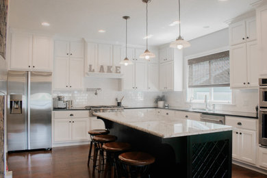 Transitional brown floor kitchen photo in Other with shaker cabinets, white cabinets, granite countertops, white backsplash, ceramic backsplash, stainless steel appliances and black countertops