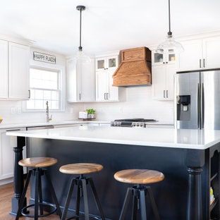 Mid-sized transitional l-shaped medium tone wood floor and brown floor eat-in kitchen photo in Baltimore with an undermount sink, shaker cabinets, white cabinets, quartz countertops, white backsplash, porcelain backsplash, stainless steel appliances, an island and white countertops