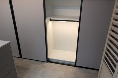 Inspiration pour un grand dressing room minimaliste avec des portes de placard grises, un sol en carrelage de céramique et un sol gris.