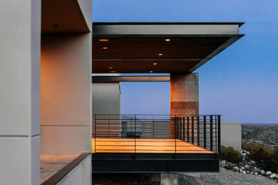 Example of a large minimalist gray one-story stucco exterior home design in Phoenix with a metal roof and a black roof