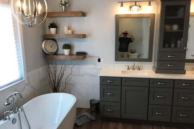 Example of a mid-sized transitional master white tile and porcelain tile medium tone wood floor and brown floor bathroom design in Cincinnati with recessed-panel cabinets, gray cabinets, a two-piece toilet, gray walls, an undermount sink, quartz countertops, a hinged shower door and white countertops