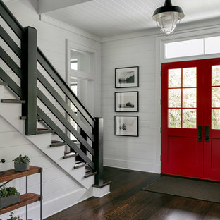 Inspiration for a large country foyer in New York with white walls, dark hardwood floors, a double front door, a red front door and brown floor.