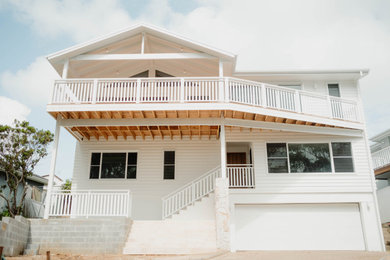 Photo of a large three-storey white house exterior in Central Coast with concrete fiberboard siding, a hip roof, a metal roof and a white roof.