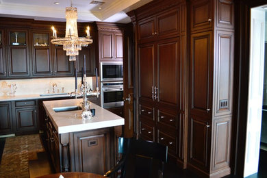 Mid-sized elegant u-shaped dark wood floor enclosed kitchen photo in Houston with an undermount sink, raised-panel cabinets, dark wood cabinets, marble countertops, stainless steel appliances and an island