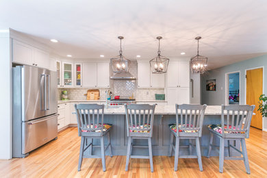 Open concept kitchen - eclectic l-shaped medium tone wood floor and brown floor open concept kitchen idea in St Louis with an undermount sink, shaker cabinets, white cabinets, quartz countertops, gray backsplash, subway tile backsplash, stainless steel appliances, an island and multicolored countertops