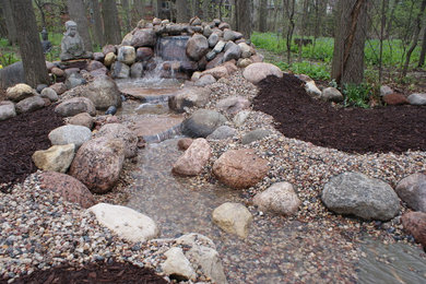 This is an example of a mid-sized traditional shade backyard stone landscaping in Chicago for fall.