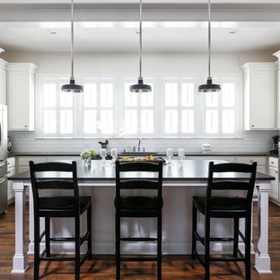 Foto di una cucina ad U chic con lavello sottopiano, ante con riquadro incassato, ante bianche, paraspruzzi bianco, paraspruzzi con piastrelle in ceramica, elettrodomestici in acciaio inossidabile, isola e parquet scuro