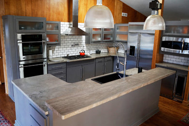 Open concept kitchen - mid-sized industrial l-shaped dark wood floor and brown floor open concept kitchen idea with a drop-in sink, flat-panel cabinets, gray cabinets, white backsplash, subway tile backsplash, stainless steel appliances, concrete countertops and two islands