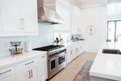 Example of a large beach style single-wall light wood floor, brown floor and coffered ceiling eat-in kitchen design in Other with an undermount sink, shaker cabinets, white cabinets, quartzite countertops, white backsplash, cement tile backsplash, stainless steel appliances, an island and white countertops