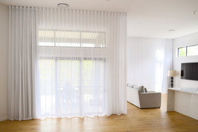 Diseño de salón abierto moderno grande con paredes blancas y suelo de madera clara