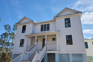Example of a large white concrete fiberboard exterior home design in Charleston with a metal roof