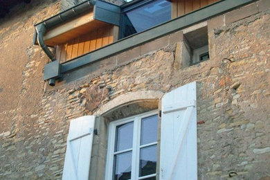 Idées déco pour une façade de maison beige campagne en pierre de taille moyenne et à deux étages et plus avec un toit à deux pans et un toit en tuile.