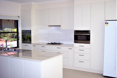 Photo of a mid-sized contemporary galley kitchen pantry in Other with a drop-in sink, flat-panel cabinets, white cabinets, laminate benchtops, white splashback, ceramic splashback, stainless steel appliances, ceramic floors and with island.