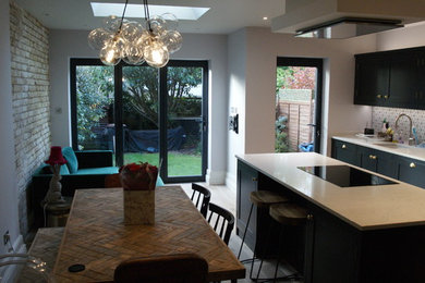 Photo of a contemporary single-wall kitchen in Kent with shaker cabinets, black cabinets, white splashback, mosaic tiled splashback, black appliances, an island, grey floors and white worktops.