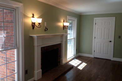 Mid-sized traditional formal enclosed living room in Detroit with green walls, dark hardwood floors, a standard fireplace, a brick fireplace surround, no tv and brown floor.