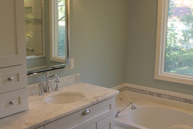 This is an example of a large traditional master bathroom in St Louis with shaker cabinets, white cabinets, a drop-in tub, a shower/bathtub combo, a two-piece toilet, gray tile, subway tile, grey walls, marble floors, an undermount sink, quartzite benchtops, white floor and a hinged shower door.