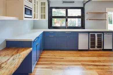 Example of a small transitional l-shaped medium tone wood floor open concept kitchen design in San Francisco with an undermount sink, shaker cabinets, blue cabinets, quartz countertops, stainless steel appliances, no island and white countertops