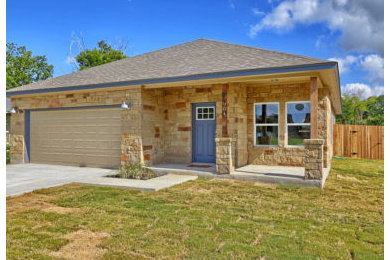 Example of a beige one-story stone house exterior design in Austin with a shingle roof