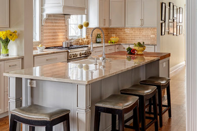 Transitional galley medium tone wood floor and brown floor enclosed kitchen photo in Chicago with a farmhouse sink, shaker cabinets, white cabinets, beige backsplash, subway tile backsplash, an island and beige countertops