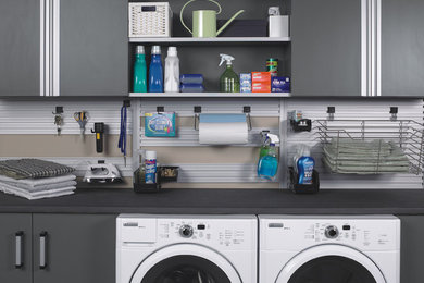 Example of a mid-sized trendy single-wall dedicated laundry room design in Charleston with flat-panel cabinets, gray cabinets, beige walls and a side-by-side washer/dryer