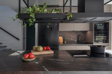 Ejemplo de cocina minimalista abierta con puertas de armario grises, encimera de cuarcita, electrodomésticos negros, una isla y encimeras grises