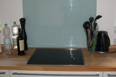 Exempel på ett avskilt, stort modernt u-kök, med släta luckor, vita skåp och träbänkskiva