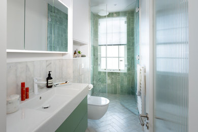 Example of a mid-sized trendy 3/4 green tile and marble tile marble floor, white floor and single-sink wet room design in London with flat-panel cabinets, green cabinets, a wall-mount toilet, white walls, a wall-mount sink, a hinged shower door, a niche and a floating vanity