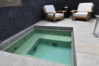 Minimalist backyard stone and custom-shaped hot tub photo in Denver